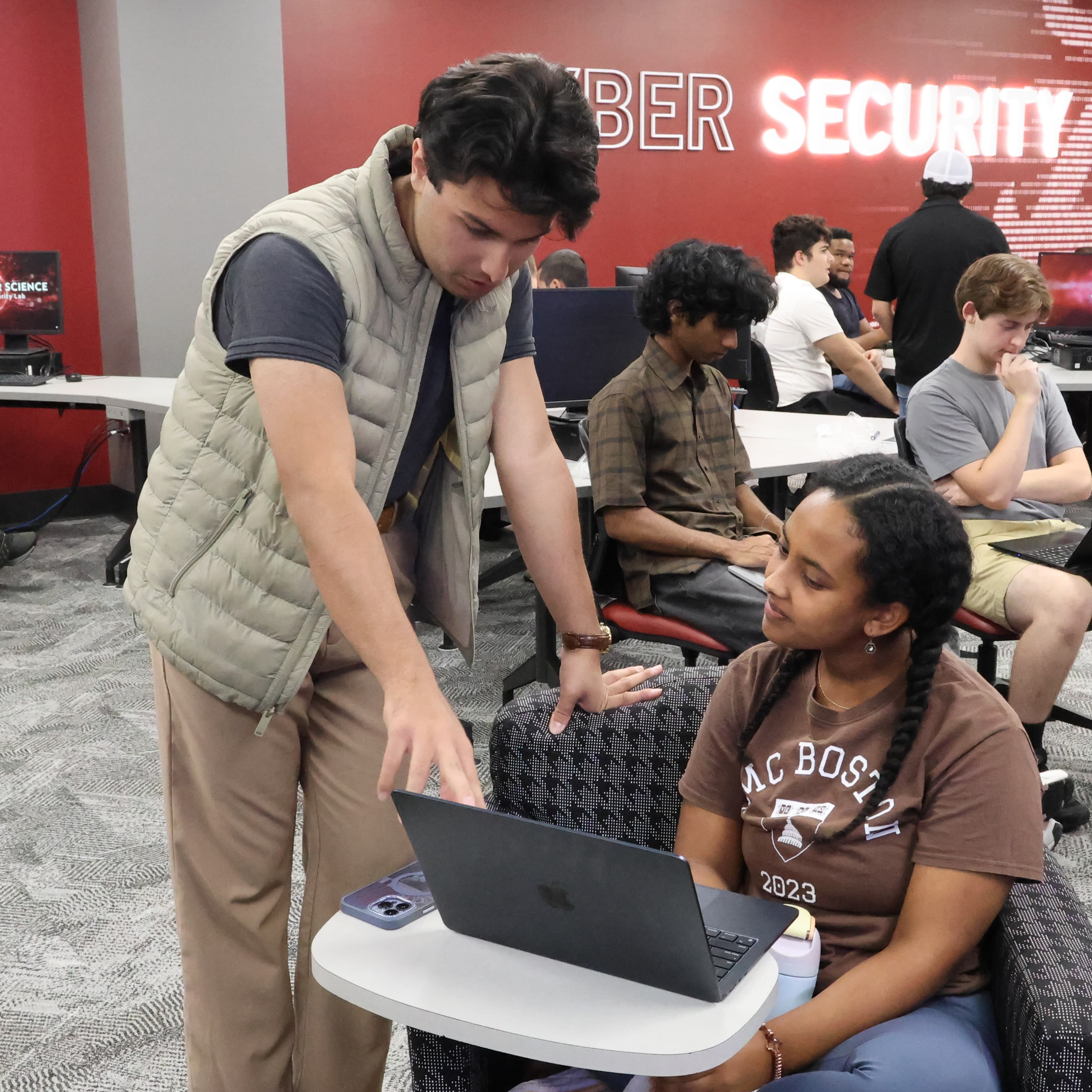 Faizan helping a workshop participant with her laptop.